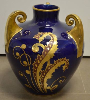 un vase bleu et doré posé sur un sol carrelé
