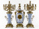 three blue and white vases and a gold candelabra