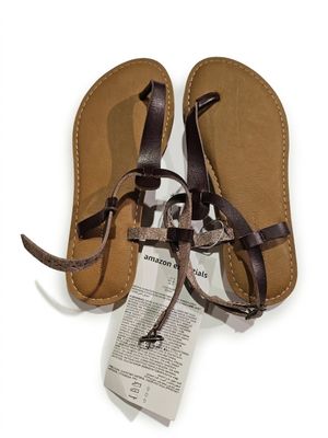 sandales en cuir avec des lanières marron sur fond blanc, accompagnées d'une étiquette de prix