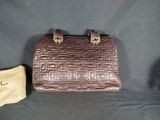 brown leather handbag with gold hardware and pouch on a black background