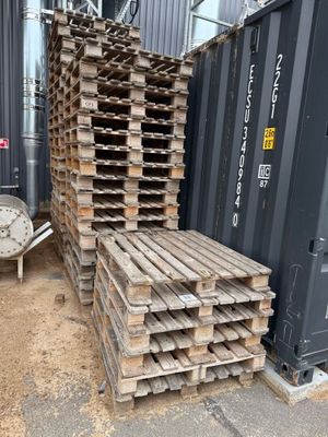 une pile de palettes en bois posée à côté d'un conteneur