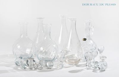cinq vases en verre posés les uns à côté des autres sur une surface blanche
