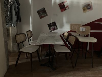 une table et des chaises dans une pièce où sont accrochés des tableaux au mur