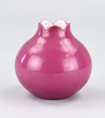 un vase violet orné d'un nœud sur le dessus, posé sur une surface blanche