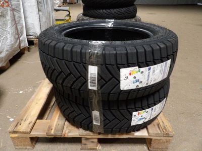 quatre pneus empilés sur une palette dans un entrepôt
