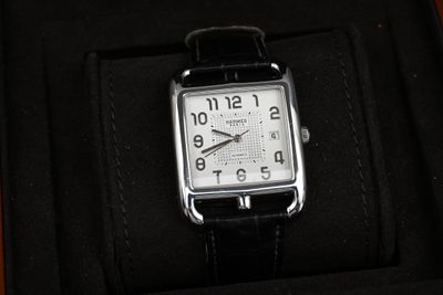 une photo d'une montre dans un coffret, avec un bracelet noir