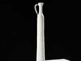 a white vase sitting on a table with a black background