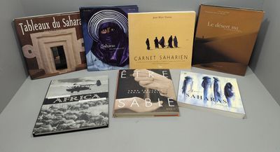 Plusieurs livres sont posés sur une table devant un mur blanc.