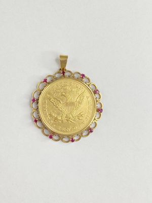 a gold coin pendant with a ruby stone in the center