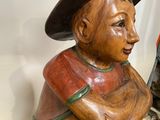 une statue en bois représentant un garçon coiffé d'un chapeau