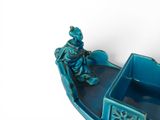 a figurine of a man sitting in a boat on the water