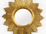 une photo d'un miroir doré en forme de soleil accroché au mur