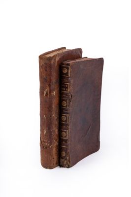 an old book with a leather cover sitting on a white surface