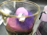 a pink duck in a cup next to a cup of coffee