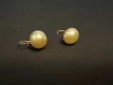 a pair of pearl earrings on a black surface