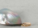 an image of a close up of a pearl pendant on a white surface