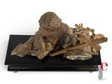 a bronze statue of a man with a clock on a table