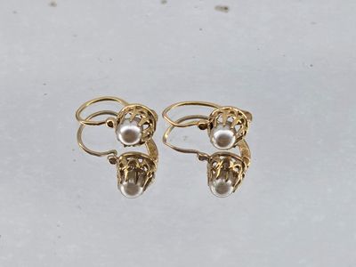 a pair of gold and pearl earrings on a white surface