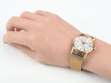 wrist shot of a woman wearing a gold watch with a white dial