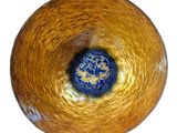 a yellow bowl with a blue center sitting on a white surface