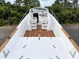 a white boat with a wooden deck in the middle of the road