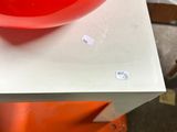 a red bowl sitting on top of a white table