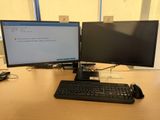 two computer monitors and a keyboard on a desk
