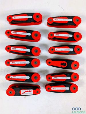 six red and black pliers are lined up on a white surface