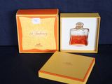 un petit flacon de parfum dans une boîte posée sur une table