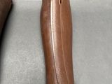 someone is holding a pair of brown leather shoes on a table