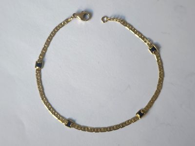 gros plan d'un bracelet en or sur une surface blanche