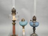 three different colored glass candlesticks are sitting on a table