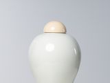 un vase blanc muni d'un couvercle en bois, posé sur une table