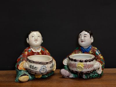 two figurines of asian men sitting on a table