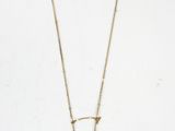 Un collier en or orné d'une pierre oplite bleue est suspendu sur un fond blanc