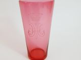 a pink glass with a crown on it sitting on a table