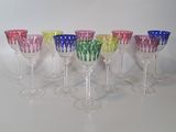 six verres à vin colorés alignés en rang sur une surface blanche