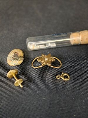 une petite bouteille accompagnée de quelques objets en or posés sur une table