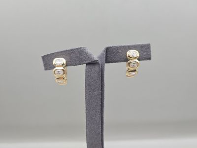 une paire de boucles d'oreilles en or et diamants, présentée sur un présentoir