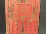 un livre rouge orné de lettres dorées, posé sur une table