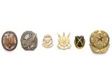 un ensemble de cinq insignes militaires sur fond blanc