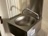 a stainless steel sink in the corner of a bathroom