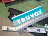 une boîte de Truvox posée par terre à côté d'une paire de chaussures et d'une autre paire de chaussures