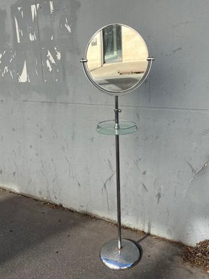 un miroir posé sur un pied près d'un mur