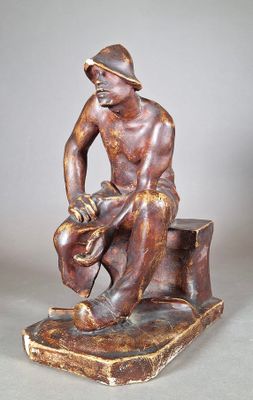 statue en bronze représentant un homme assis sur un rocher, coiffé d'un chapeau