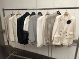 a lot of jackets hanging on a rack in a room