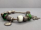 un bracelet en argent orné de perles vertes et de breloques