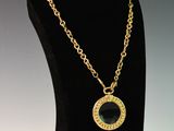 a black and gold necklace with a circle pendant on a mannequin