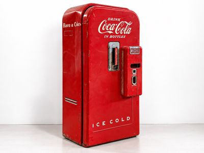 a red coca cola machine sitting on the floor