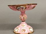 un petit vase rose bordé d'or posé sur une table